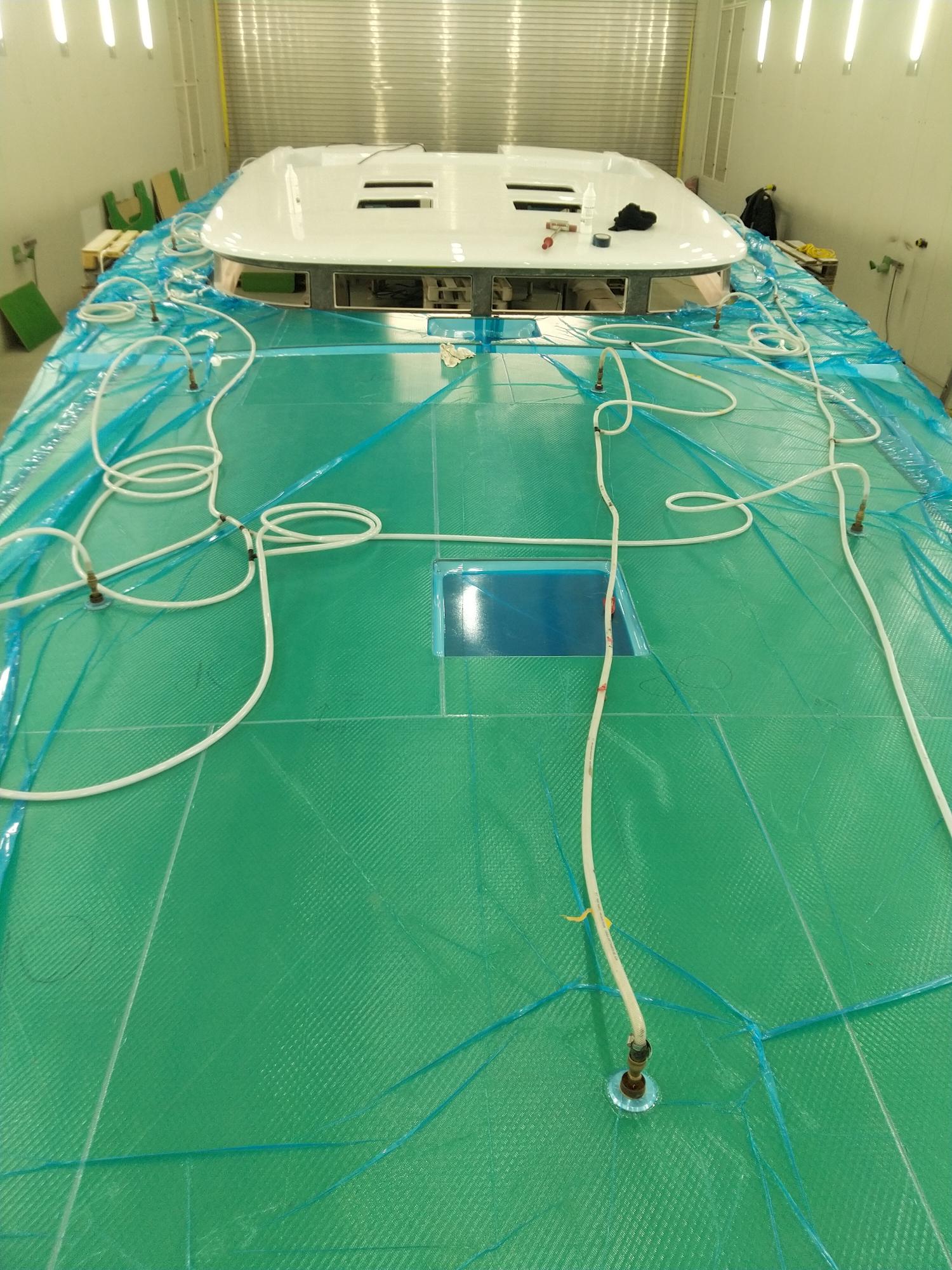 Image montrant le processus de pose sous vide d'un revêtement de pont en teck synthétique sur un bateau.